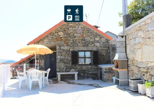 a building with a table and chairs and an umbrella at Sobrado Fonseca in Paredes do Rio