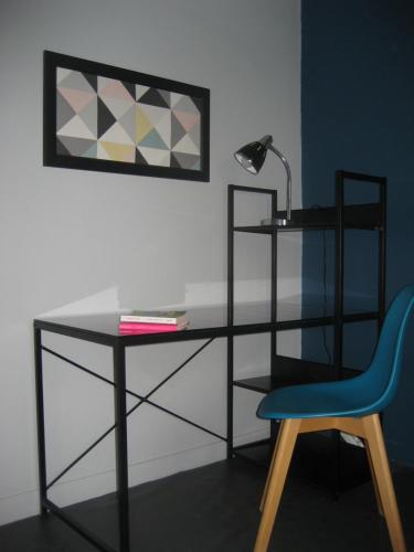 un bureau avec une lampe et une chaise bleue dans l'établissement Appart agréable 2 chambres Quartier calme toutes commodités, à La Rochelle