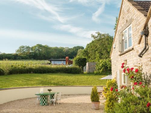 a garden with a table and a house at Vine Cottage in Shepton Mallet