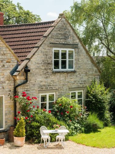 a house with two chairs and a table in front of it at Vine Cottage in Shepton Mallet