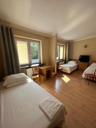 a bedroom with two beds and a desk and two windows at Zajazd Bias in Wyszków