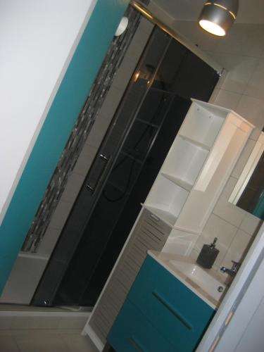 La salle de bains est pourvue d'une porte bleue et d'un miroir. dans l'établissement Appart agréable 2 chambres Quartier calme toutes commodités, à La Rochelle
