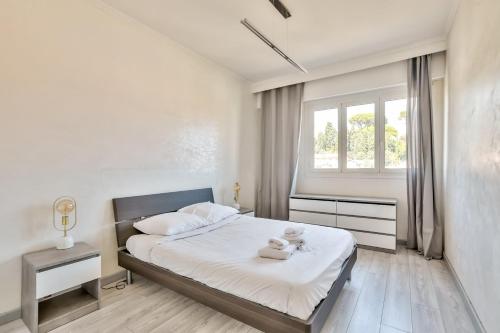 une chambre blanche avec un lit et une fenêtre dans l'établissement Superbe T2 avec terrasse et parking, à Nice