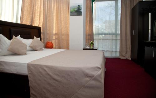 a bedroom with a bed with white sheets and a window at Hotel Metropol in Piteşti