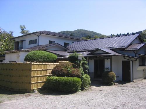 dom z płotem i krzakami przed nim w obiekcie Fuji-Hakone Guest House w mieście Hakone