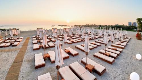 a row of lounge chairs and umbrellas on a beach at Hotel Malibu in Mamaia