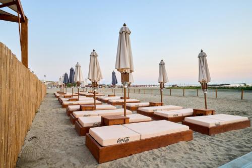 a row of chaise lounges with umbrellas on the beach at Hotel Malibu in Mamaia