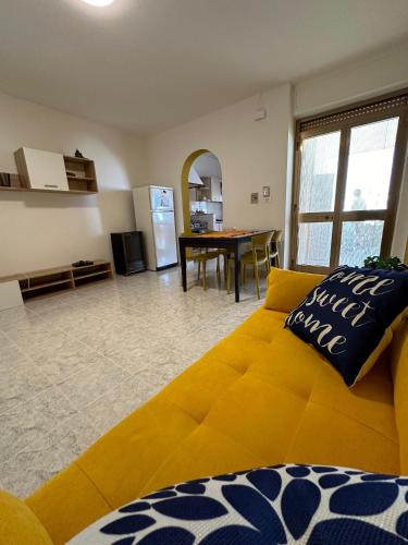 a living room with a yellow couch and a kitchen at SOFIA APPARTAMENTO Lido Marini in Lido Marini