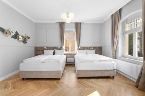 two beds in a bedroom with white walls and wood floors at Residenz Hugo in Bad Schandau