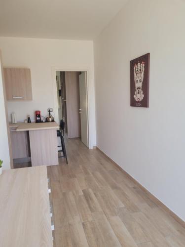 a living room with a white wall and a wooden floor at HOUSE AIRPORT Catania in Catania