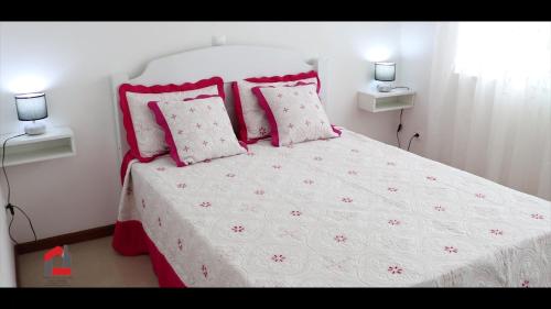 a bedroom with a white bed with pink pillows at Guest House Lina Elisa in Mindelo
