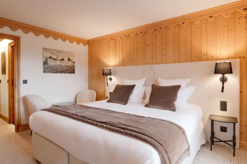 a large white bed in a room with wooden walls at La Ferme du Golf in Megève