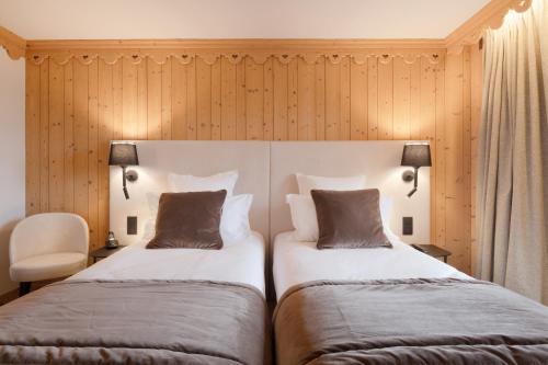 two beds in a room with wooden walls at La Ferme du Golf in Megève