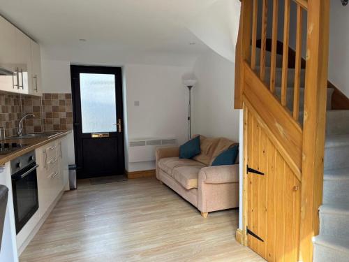 a living room with a couch and a stair case at Clock Tower Cottage in Nailsworth