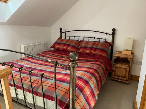 a bed with a striped comforter in a bedroom at Clock Tower Cottage in Nailsworth