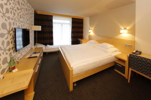 a hotel room with a large bed and a desk at Wellness hotel Horal, Velké Karlovice in Velké Karlovice