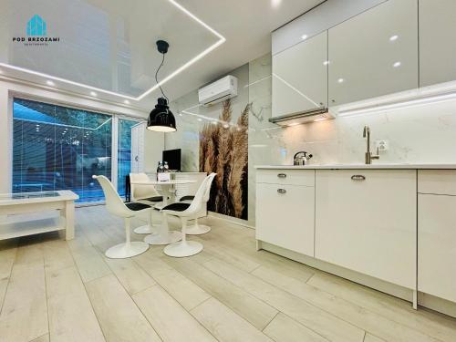 a kitchen with white cabinets and a table and chairs at Pod Brzozami Apartamenty Gąski in Gąski