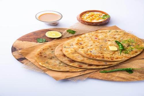 two pita breads on a wooden cutting board with sauce at FabExpress Amber Corp Inn - Nr NESCO Exhibition Center in Mumbai