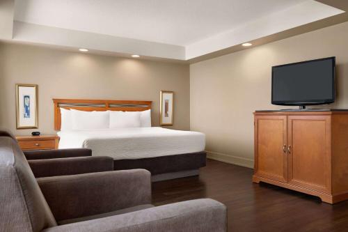 a hotel room with a bed and a flat screen tv at Royal Hotel Calgary, Trademark Collection by Wyndham in Calgary