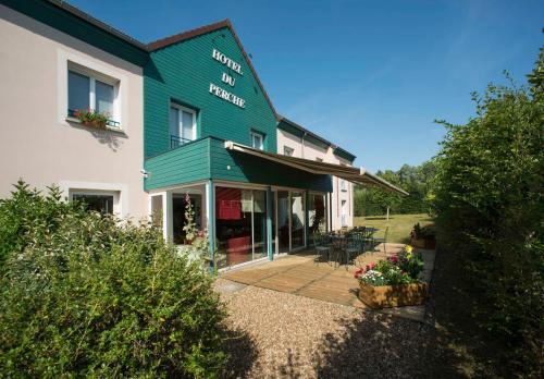 a green building with a patio in front of it at Brit Hotel Du Perche in Nogent-le-Rotrou