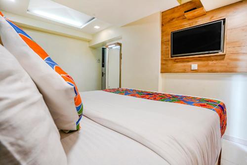 a bedroom with two beds and a tv on the wall at FabExpress Amber Corp Inn - Nr NESCO Exhibition Center in Mumbai
