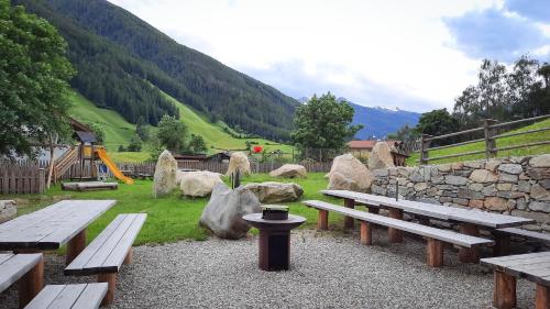 a group of picnic benches in a park with a hill at Koasa-Hof Ganzes Ferienhaus und Sauna 5 Zimmer 240mq in Cadipietra