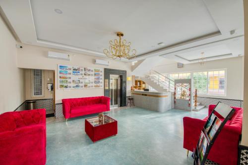 a living room with red chairs and a red table at Hotel Sunlight in Puducherry