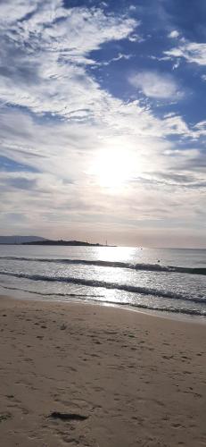 a sandy beach with the sun shining on the ocean at Sea Apartament Kristal Beach,Nessebar in Nesebar