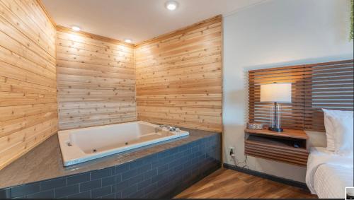 a bathroom with a tub in a room with wooden walls at Lakeside Bliss 1BR Enchanting Master Suite in Osage Beach