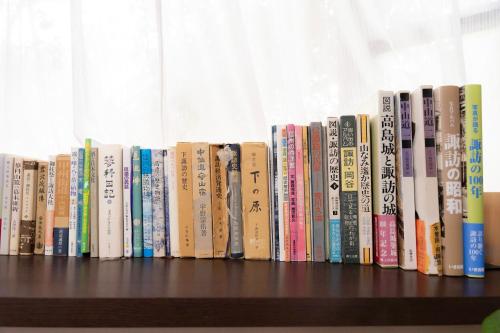 a row of books sitting on a shelf at 一組貸切宿 岡村 弐番館 limited to 1group per day 一棟まるまる貸切 in Suwa