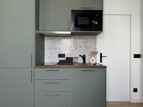 une cuisine avec un évier et un micro-ondes dans l'établissement Appartement Bien Équipé dans un Quartier Prisé, à Boulogne-Billancourt