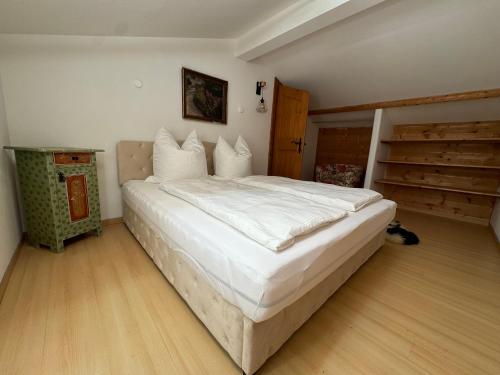 a bedroom with a large white bed and a wooden floor at AU-4 Ferienwohnung in Lofer
