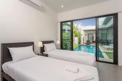 2 Betten in einem Zimmer mit Poolblick in der Unterkunft Tropical 3BR Pool Villa Nga Chang NC10, Gated Residence, 10 min Drive to Nai Harn Beach in Ban Saiyuan (1)