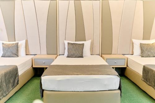 two beds in a room with white walls at Hotel Malibu in Mamaia