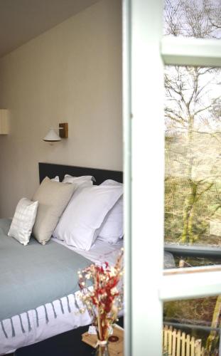 a bed with white pillows sitting next to a window at La Maison du Gasseau in Saint-Léonard-des-Bois