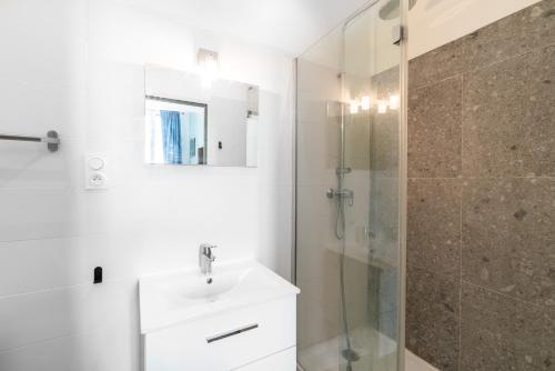 une salle de bain blanche avec un lavabo et une douche dans l'établissement L'Eden T5 - 5min de la gare - vieux port, à Marseille