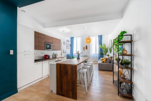 une cuisine avec des armoires blanches et un îlot de cuisine avec des tabourets dans l'établissement L'Eden T5 - 5min de la gare - vieux port, à Marseille