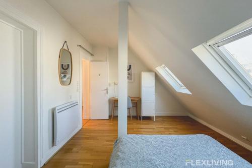 Cette chambre mansardée comprend un lit et un escalier. dans l'établissement Flexliving - room - Bausset, à Paris