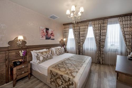 a bedroom with a large bed with curtains and a chandelier at Perapolis Hotel in Istanbul