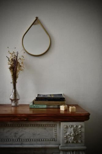 a table with a vase of flowers and a mirror at La Maison du Gasseau in Saint-Léonard-des-Bois
