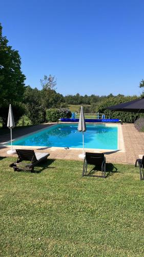 - une piscine avec 2 chaises longues et 2 parasols dans l'établissement Puyleger, à Saint-Privat-des-Prés