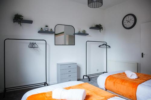 a bedroom with two beds and a clock on the wall at Spacious 2-Bedroom Flat with 4 Beds, Ideal for Contractors, Long Stay Deals in Wallasey