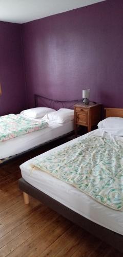 - 2 lits dans une chambre avec un mur violet dans l'établissement La huberdiere, à Surville