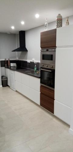 une cuisine avec des armoires blanches et une cuisinière dans l'établissement La huberdiere, à Surville