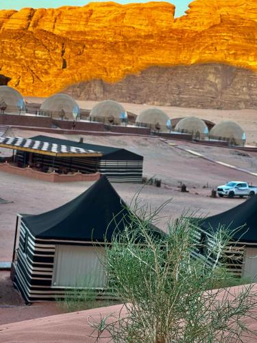 a group of tents in a parking lot next to a mountain at RUM STARDUST lUXURY CAMP in Wadi Rum