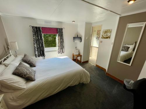 a bedroom with a large white bed and a window at Celtic Lodges in Thurso