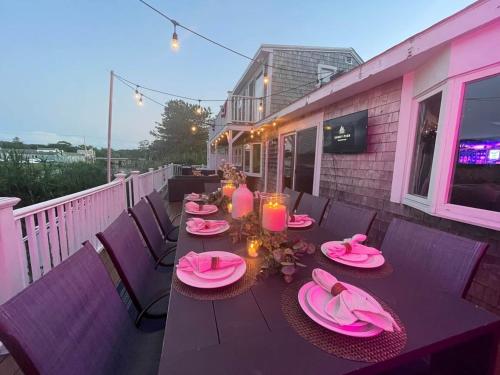 a table with pink plates and candles on a deck at Waterfront, Hottub, Petsok, Firepit, Pooltable in Dennis