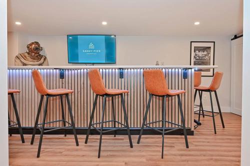 a bar with four stools in front of a tv at 5mins2beach, Hottub, Gameroom, Petsok in Dennis