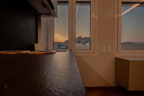 a kitchen with two windows and a counter with plates on it at Unique 2BR Penthouse with Stunning Acropolis View in Athens