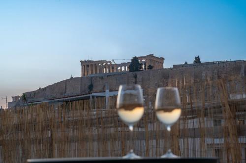 two glasses of white wine in front of a fence at Unique 2BR Penthouse with Stunning Acropolis View in Athens